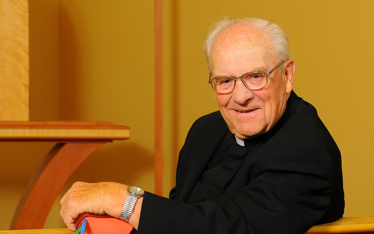 Archbishop Hunthausen in a pew smiling at the camera