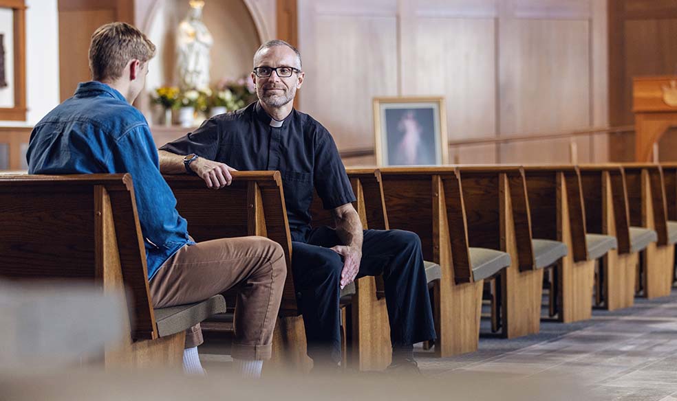 Student and Father Marc talking one on one in the chapel