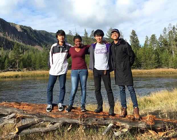 Diverse group of four students smiling in front of Madison River