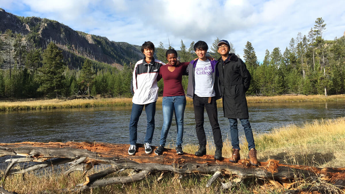 Diverse group of four students smiling in front of Madison River