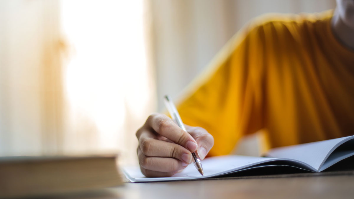 Student writing with pen and paper