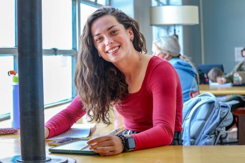 Female student studying and smiling inside with iPad