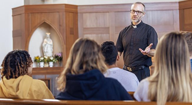 Minister lecturing in a chapel to a group of students