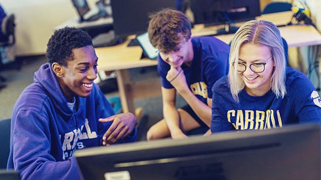 Three students engaged in discussion at a computer