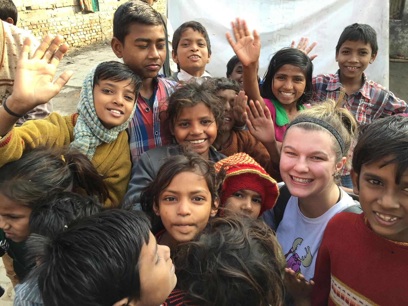 Carroll College student abroad surrounded by children