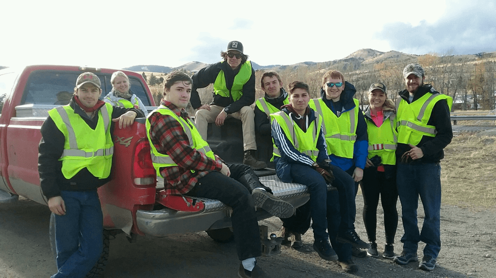 ASCE students sitting on the back of a truck getting ready to clean up interstate 15