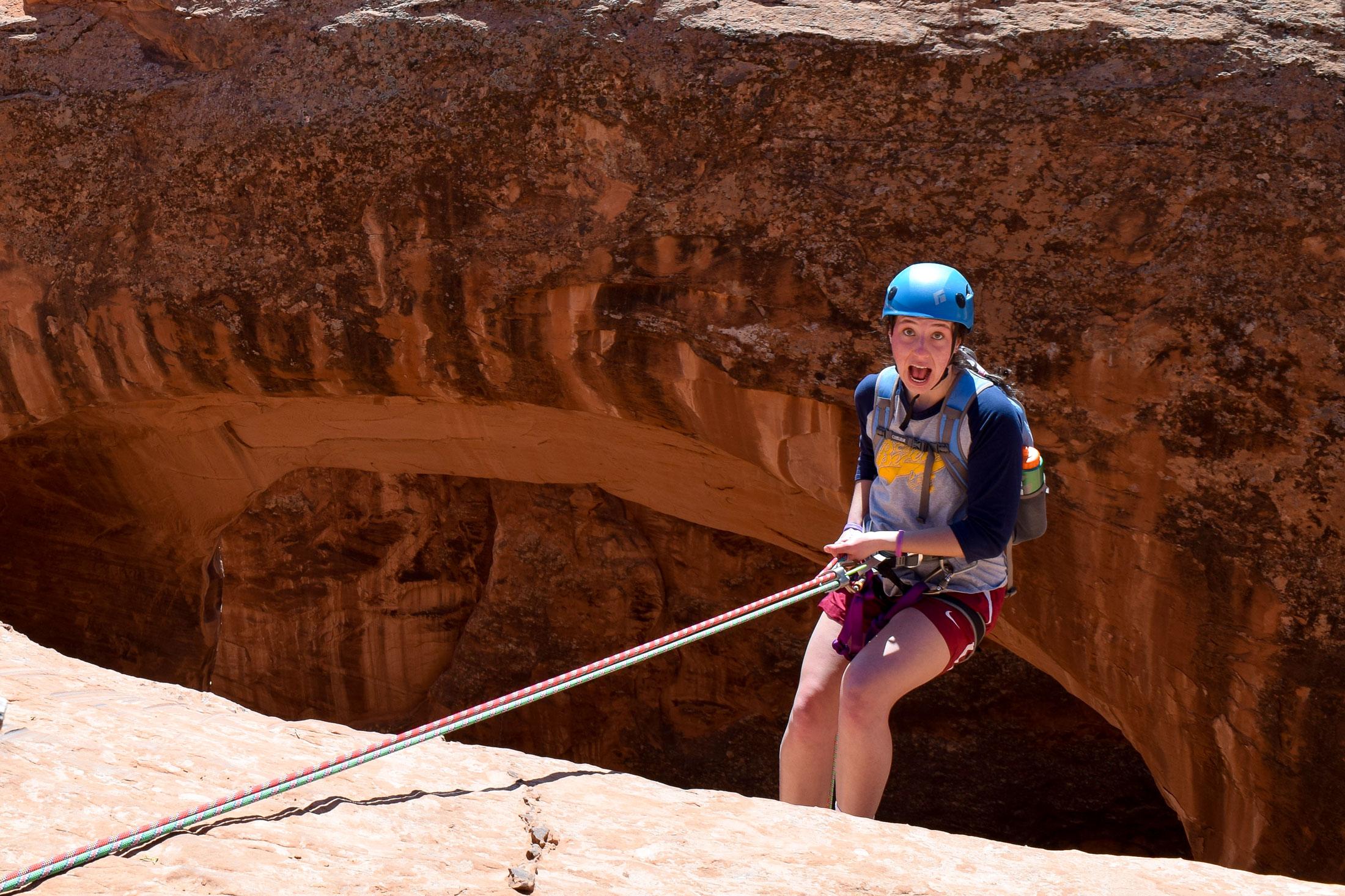 Elle Barta repelling down a large rock in the desert