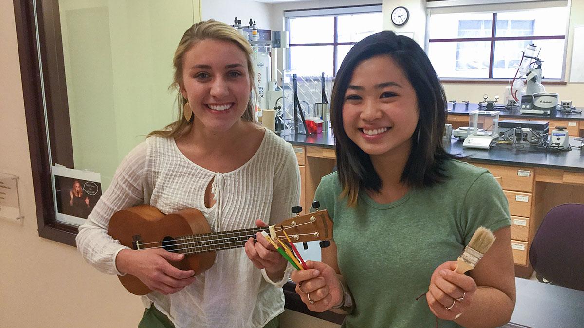 Lauren Rhoda and Victoria Kong holding instruments and brushes