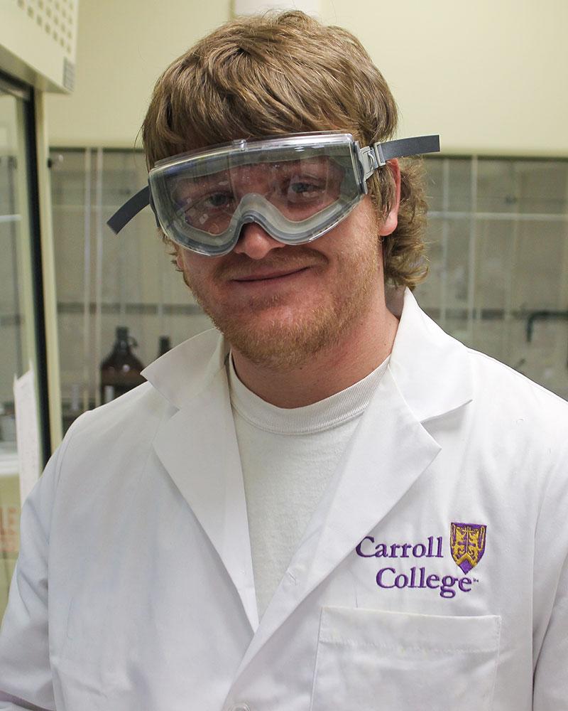 Portrait of Dustin Williams wearing safety goggles and a lab coat